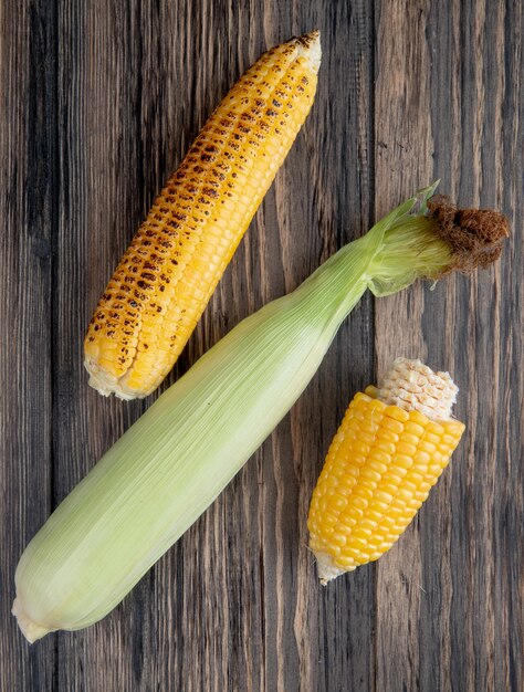 Top view of cooked and uncooked corns on wood