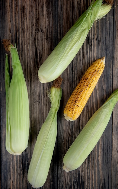 Top view of cooked and uncooked corns on wooden surface 1