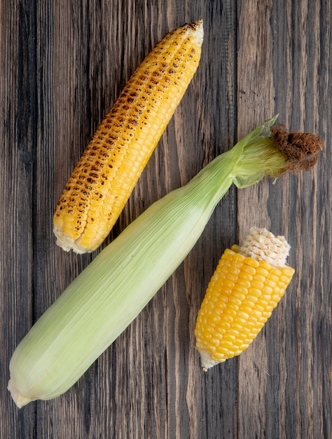Free photo top view of cooked and uncooked corns on wooden surface