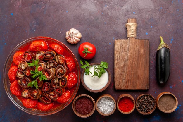 Top view cooked vegetable meal delicious tomatoes and eggplants with seasonings on dark desk