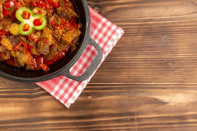 Вид сверху приготовленной овощной еды, включая овощи и мясо внутри на коричневом столе