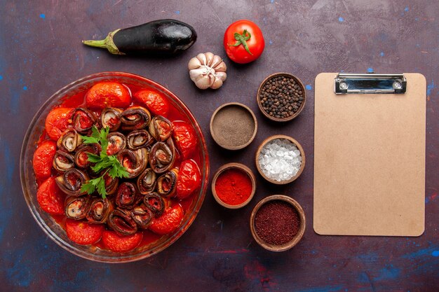 Top view cooked vegetable meal tomatoes and eggplants with seasonings on dark desk