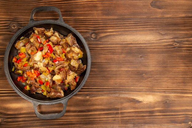 Top view cooked vegetable meal with meat and sliced bell peppers on the brown rustic desk