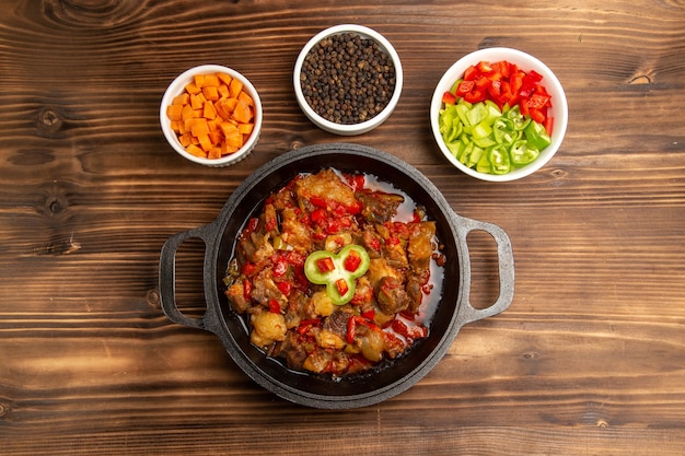 Вид сверху приготовленная овощная еда с приправами и нарезанным болгарским перцем на коричневом столе