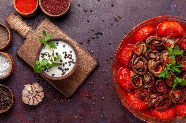 Top view cooked vegetable meal with seasonings and sour cream on dark surface