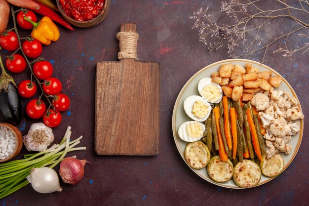 Top view cooked vegetables with egg meal and fresh vegetables on a dark space