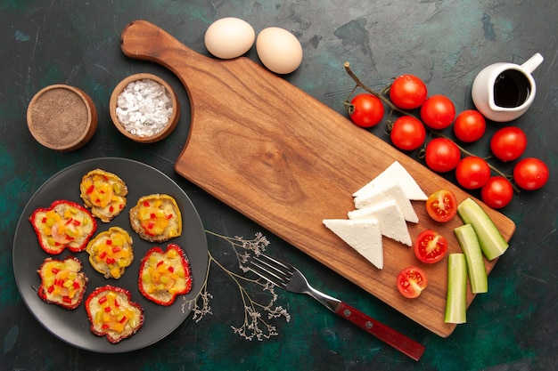 Top view cooked vegetables with raw eggs and fresh tomatoes on dark surface