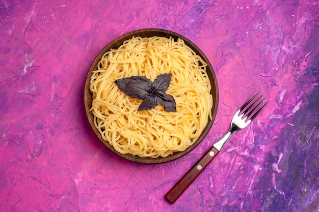 Вид сверху приготовленные вкусные спагетти внутри тарелки на розовом столе, тесто, блюдо из макарон
