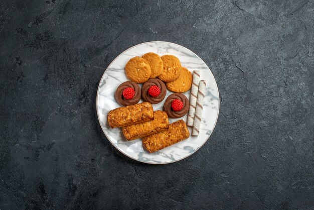 灰色のスペースのプレート内のトップビューのクッキーとケーキ