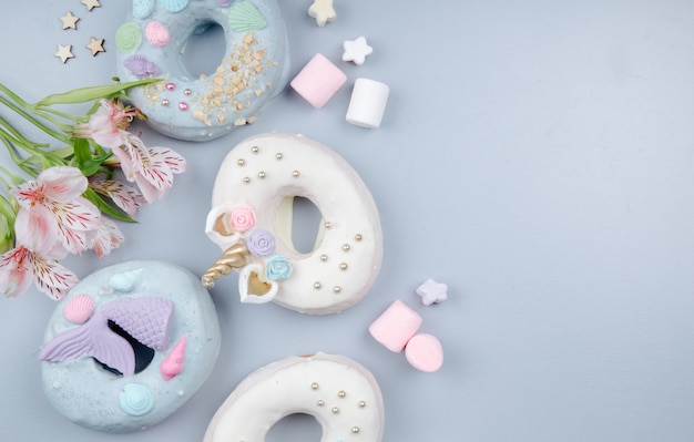 Top view of cookies and candies on left side decorated with flowers on purple with copy space