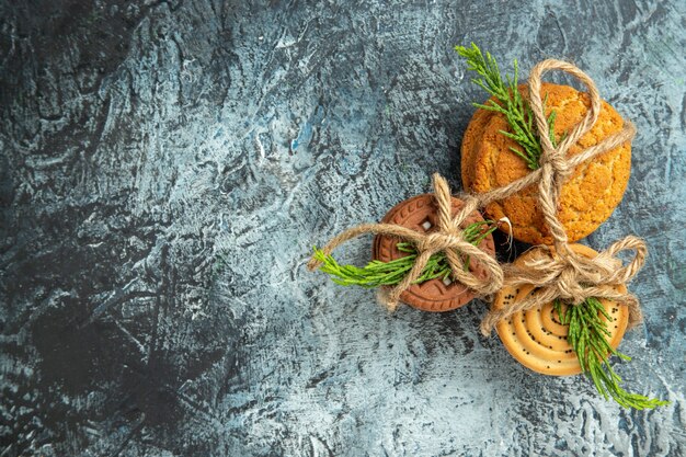 Top view cookies tied with ropes and pinetree leaves on grey surface copy space