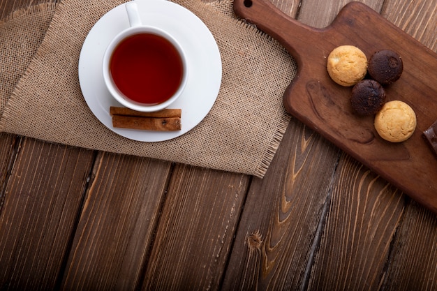 Top view of cookies on a wooden cutting board with a cup of tea on rustic