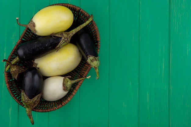 Top view  copy space black and white eggplant in basket on green background