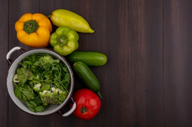 Foto gratuita vista dall'alto copia spazio broccoli in una casseruola con prezzemolo e cetrioli e peperoni su fondo in legno