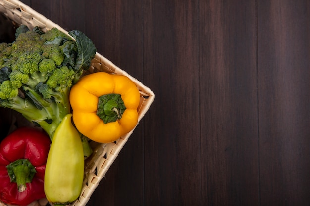 Top view  copy space broccoli with bell peppers in basket on wooden background