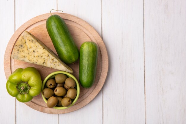 Top view  copy space cheese with cucumbers and bell peppers on a stand with olives on a white background