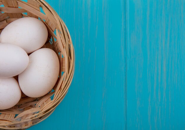 Top view  copy space chicken eggs in basket on turquoise background