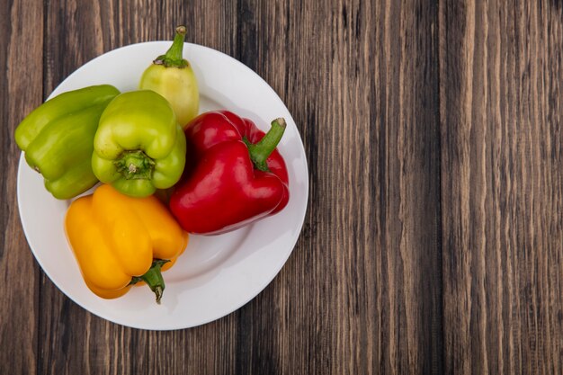 Top view  copy space colored bell peppers on a plate  on a wooden background