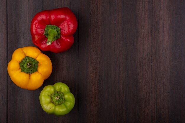 Top view  copy space colored bell peppers red  yellow and green on wooden background