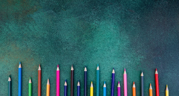 Top view copy space colorful pencils on a green background
