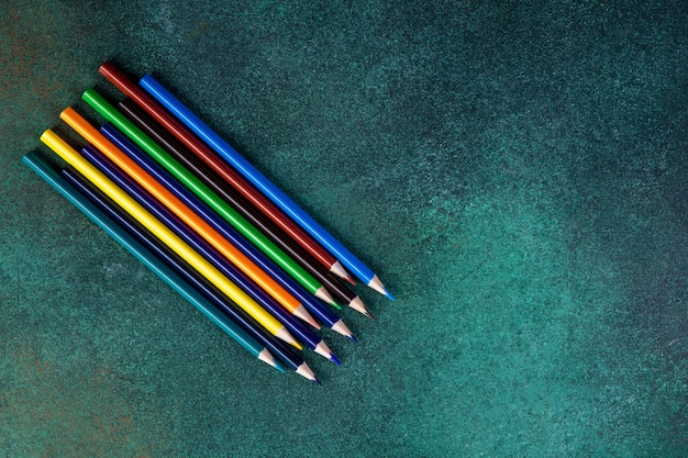 Top view copy space colorful pencils on a green background