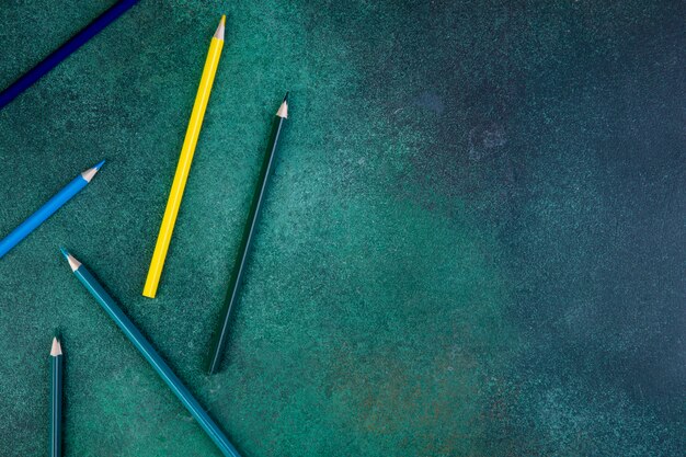 Вид сверху копией пространства красочных карандашей на зеленом фоне