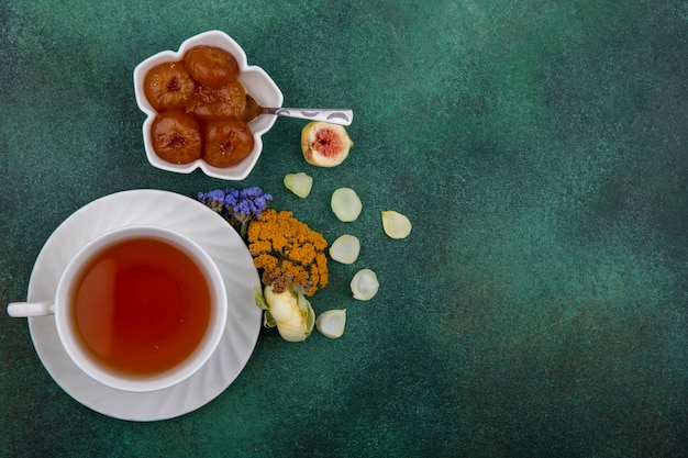 Бесплатное фото Вид сверху копия космической чашки чая с инжирным вареньем и цветами на зеленом фоне