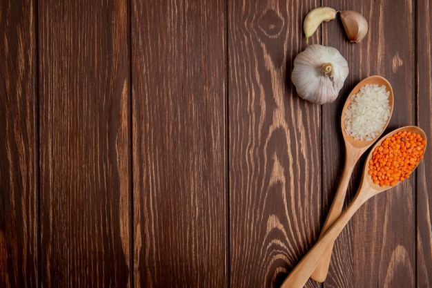 Top view copy space garlic with a spoon of lentils and rice on a wooden background