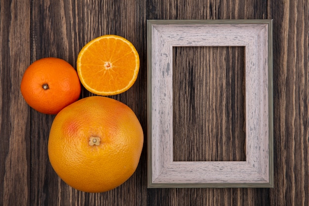 Вид сверху копией космического грейпфрута с апельсинами и серой рамкой на деревянном фоне