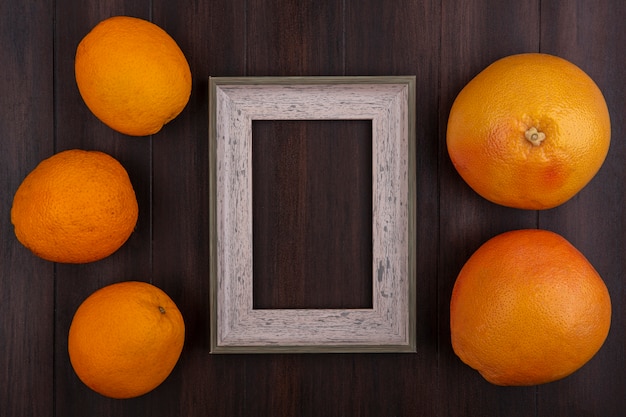 Top view  copy space grapefruits with oranges and gray frame on wooden background