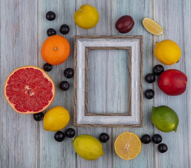 Top view  copy space gray frame with cherry plum  orange  peach  plum  lemon and lime on gray background