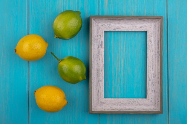 Top view  copy space gray frame with lemons and limes on a turquoise background