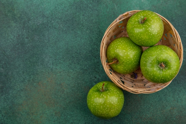 Top view  copy space green apples in a basket on a green background