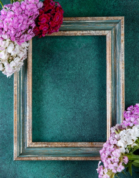 Top view copy space green-gold frame with colorful flowers on the edges on green