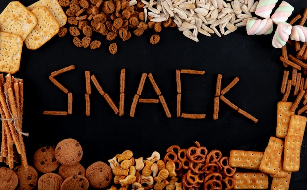 Free photo top view copy space inscription snacks with crackers seeds and cookies on a black background