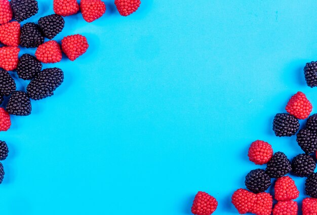 Top view copy space marmalade in the form of raspberries and blackberries on a blue background