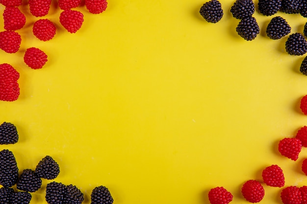 Top view copy space marmalade in the form of raspberries and blackberries on a yellow background