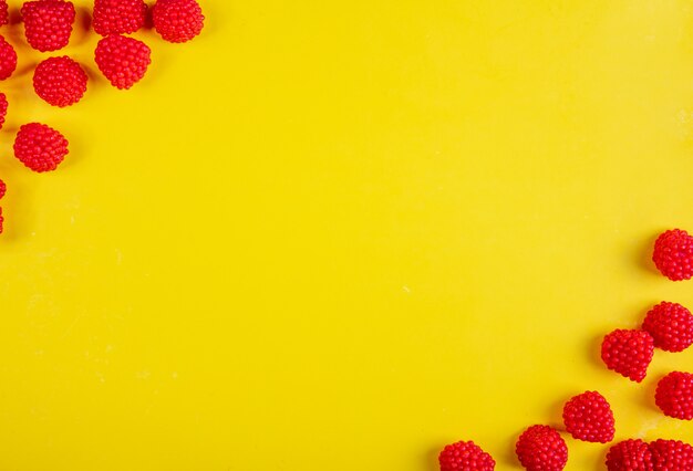 Top view copy space marmalade in the form of raspberries on a yellow background