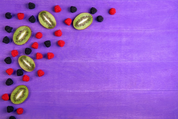 Top view copy space marmalade in formalines and blackberries with kiwi slices on a purple background