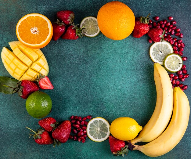 Top view  copy space mix of fruits mango  banana  strawberries  lemon  orange  on a green background