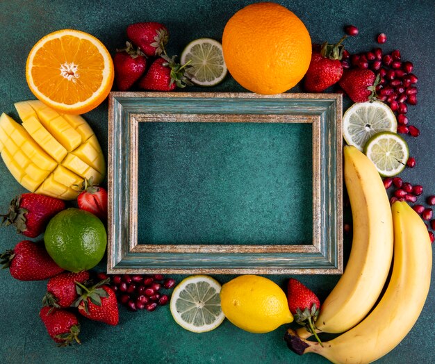 top view copy space mix of fruits mango banana strawberries lemon orange with frame on green