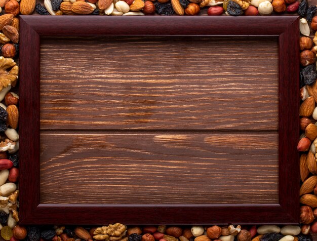 Top view copy space mix of nuts with raisins and wooden frame on a wooden background