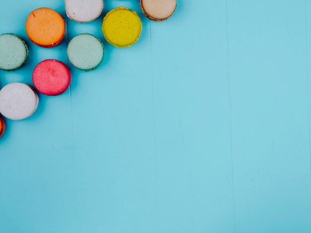 Top view copy space multicolored macarons on a blue background