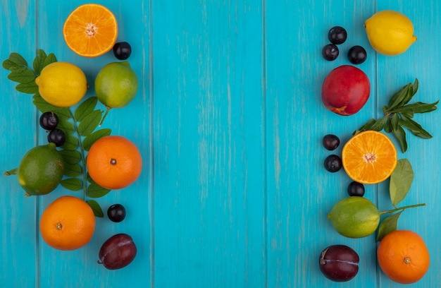 Top view  copy space oranges   with cherry plums  lemons  limes and plums on a turquoise background