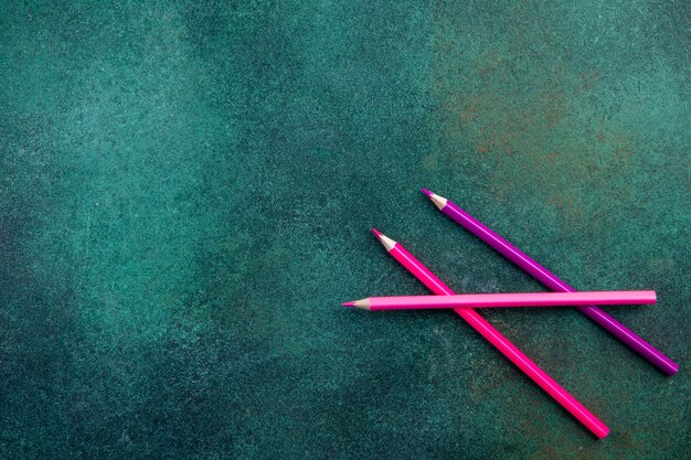 Вид сверху копией пространства розовыми карандашами на зеленом фоне