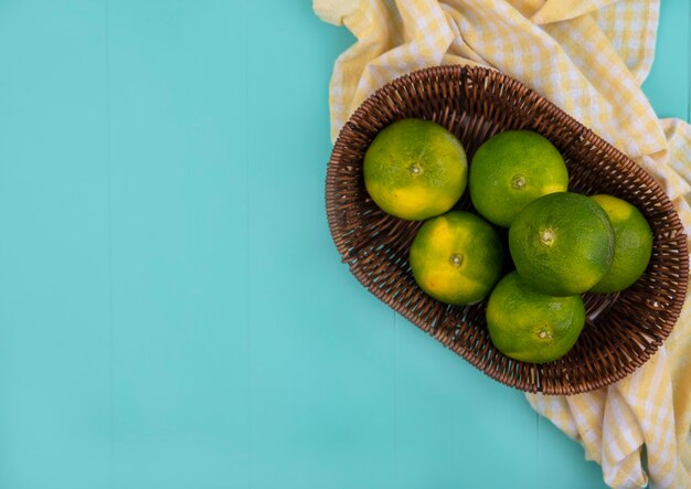 Top view copy space tangerines in a basket on a yellow checkered towel on a blue wall