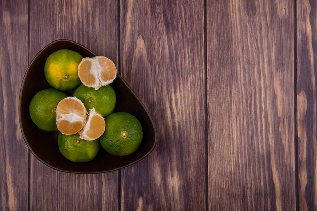 Top view copy space tangerines in bowl with peeled wedges on wood wall