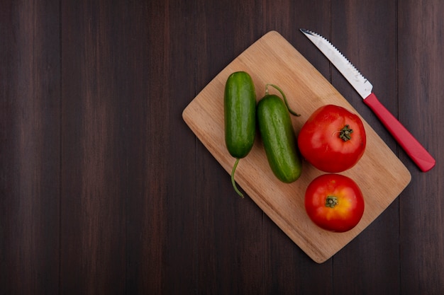 Top view  copy space tomatoes with cucumbers and knife on cutting board on wooden background
