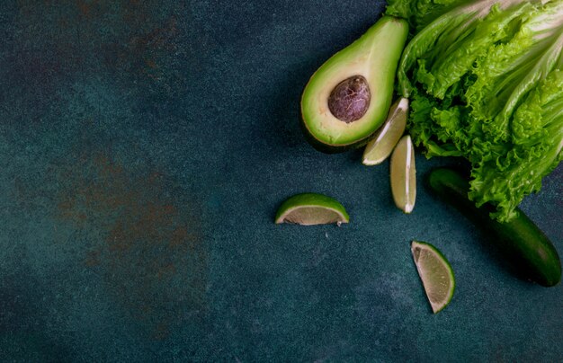 Top view copy space vegetables of avocado lemon cucumber and lettuce on a dark green background