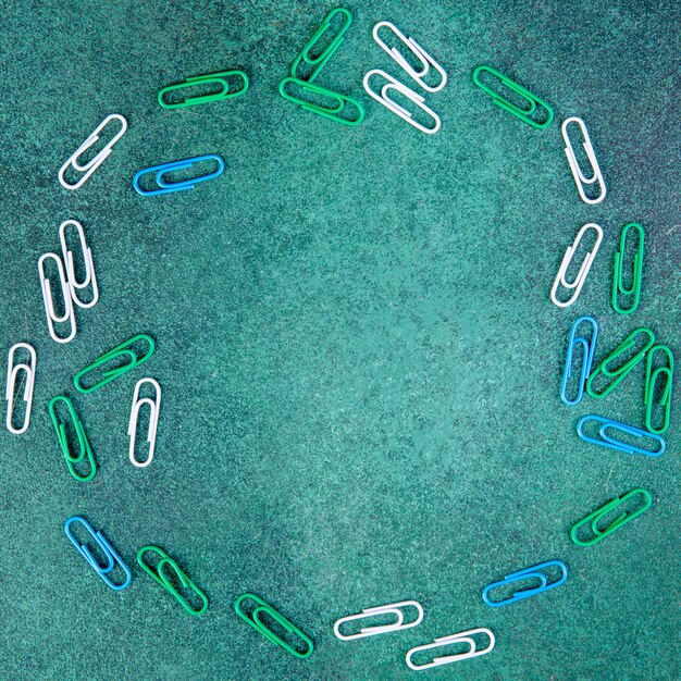 Top view copy space white green and blue paper clips on a green background